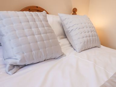 A bed with two white square pillows and white bedding at Maypole Cottage in Fylingthorpe