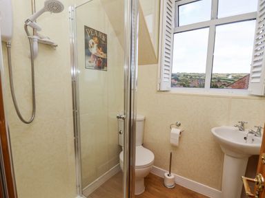 A bathroom with a shower enclosure toilet sink and window at Maypole Cottage in Fylingthorpe
