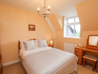 A bedroom with a bed a wooden dressing table and a window at Maypole Cottage in Fylingthorpe