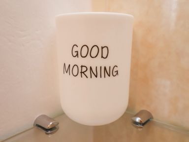A white cup with the words good morning on a glass shelf with metal brackets
