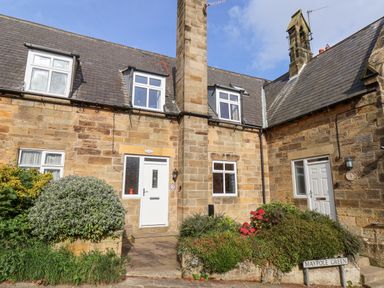 Stone cottages with white doors and windows and plants near the entrances at Maypole Cottage in Fylingthorpe
