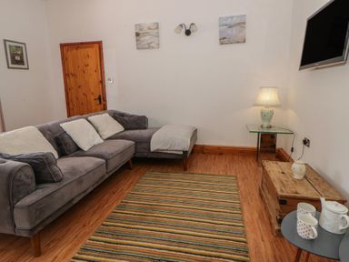A living room with a sofa and a table at Swallows Retreat in Tenby