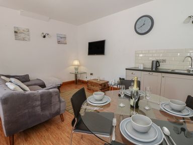 A living room with a dining area and kitchen unit at Swallows Retreat in Tenby