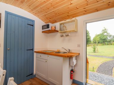 A kitchen corner with wooden countertop and sink a blue wooden door and a door open to a garden at Sunflower Sparnon Gate near Illogan