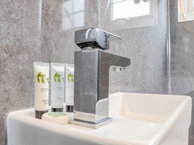 A bathroom sink with a chrome faucet and toiletries at Sunflower Sparnon Gate near Illogan