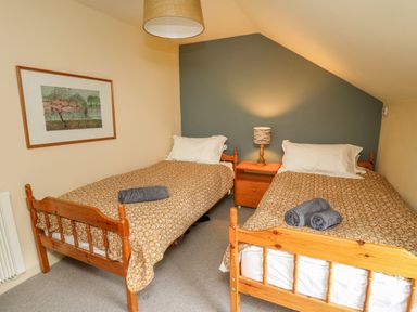 A bedroom with two single beds a nightstand with a lamp and a framed picture on the wall at Taibach in Dinas Cross