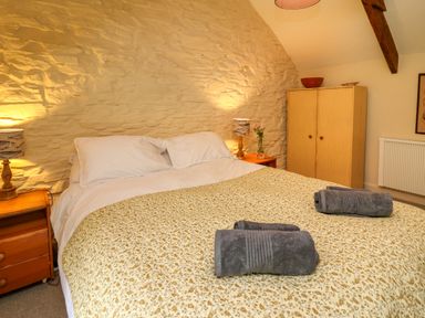 A bedroom with a double bed two bedside tables with lamps and a wooden wardrobe at Taibach in Dinas Cross