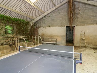 An indoor space with a ping pong table a ladder a bench and old metal railings Taibach Dinas Cross