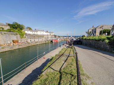 A harbor with boats docked along a canal and stone buildings on both sides at Quay House in Charlestown