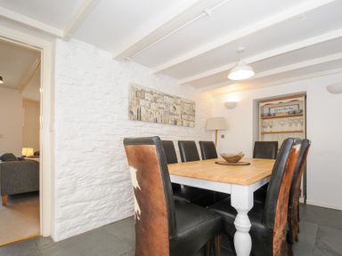 A dining room with a wooden table and eight chairs with leather and fur covers at Quay House Charlestown