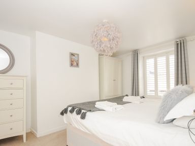 A bedroom with a bed towels a chest of drawers a wardrobe and a window with curtains at Quay House in Charlestown
