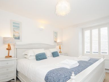 A bedroom with a large white bed blue cushions white folded towels and bedside tables with lamps at Quay House in Charlestown