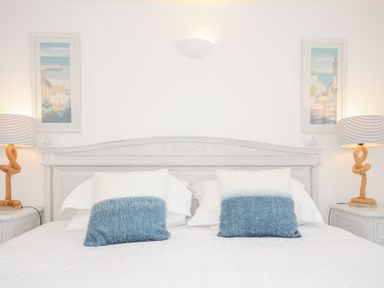A bedroom with a bed with two pillows two table lamps and two framed pictures at Quay House in Charlestown