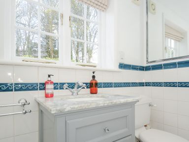 A bathroom sink with a marble countertop two soap dispensers and a mirror above the toilet at Quay House in Charlestown