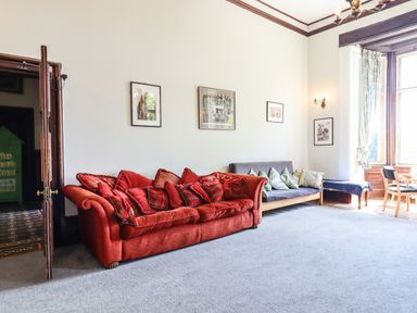 A living room with a red sofa and a gray sofa with cushions and framed pictures on the wall at Nethercott House in Iddesleigh near Hatherleigh