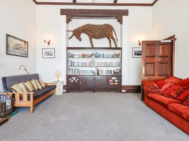 A living room with sofas bookshelves and a woven animal decoration at Nethercott House in Iddesleigh near Hatherleigh