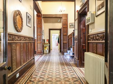 A hallway with patterned tiled floor wooden wall panels and a staircase at Nethercott House in Iddesleigh near Hatherleigh