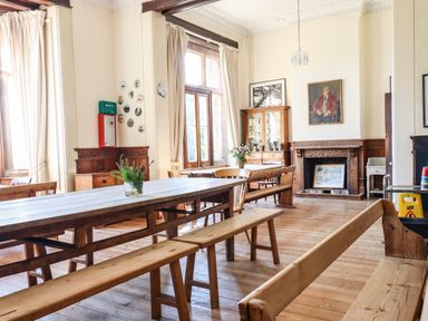 A dining room with wooden benches and tables with flowers in vases at Nethercott House in Iddesleigh near Hatherleigh