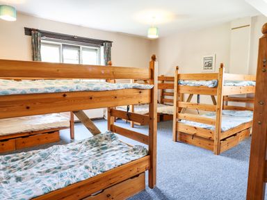 A bedroom with wooden bunk beds and blue patterned bedding at Nethercott House in Iddesleigh near Hatherleigh