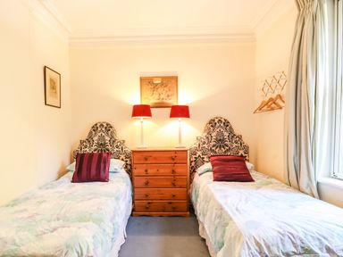 A bedroom with two single beds with patterned headboards and a wooden dresser with two lamps Nethercott House Iddesleigh near Hatherleigh