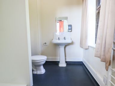 A bathroom with a toilet sink and window with curtains at Nethercott House in Iddesleigh near Hatherleigh