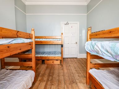 A bedroom with two wooden bunk beds and a white door at Nethercott House in Iddesleigh near Hatherleigh