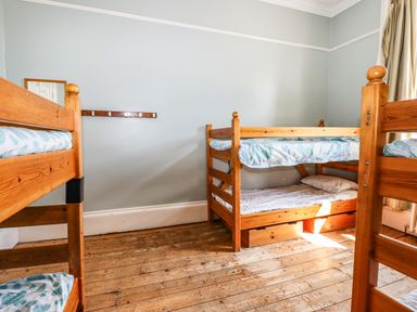 A bedroom with three wooden bunk beds and a wooden floor at Nethercott House in Iddesleigh near Hatherleigh