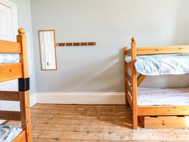 A room with wooden bunk beds a wall-mounted mirror and a wooden floor at Nethercott House in Iddesleigh near Hatherleigh
