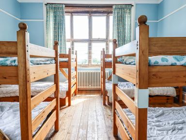 A bedroom with four wooden bunk beds and a large window at Nethercott House in Iddesleigh near Hatherleigh