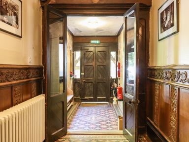 A hallway with wooden double doors opened to an entrance with a patterned tiled floor at Nethercott House in Iddesleigh near Hatherleigh