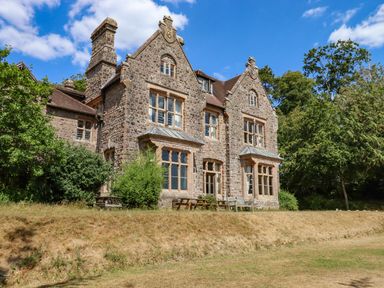 A stone house with large windows and a chimney surrounded by trees at Nethercott House Iddesleigh near Hatherleigh