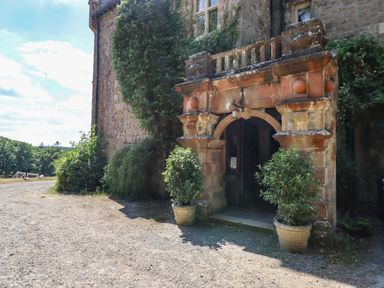 An entrance with stone archway and two potted plants outside a stone building at Nethercott House in Iddesleigh near Hatherleigh