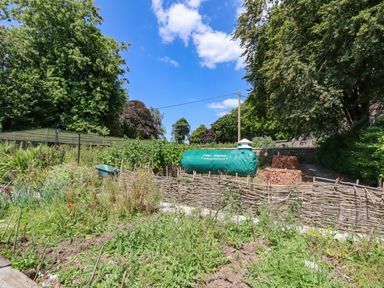 A garden area with plants wooden fences a green compost bin and a pile of bricks at Nethercott House in Iddesleigh near Hatherleigh