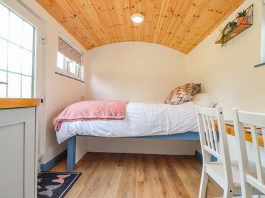 A small bedroom with a single bed wooden ceiling and a desk with two chairs at Rose in Illogan