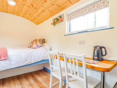 A bedroom with a single bed white chairs and a wooden desk with an electric kettle at Rose Illogan