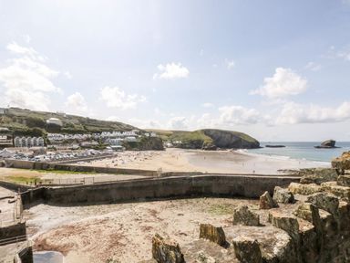 A beach with people and houses on a hillside near the water at Rose in Illogan