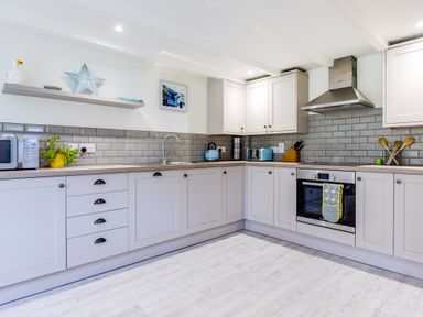 A kitchen with cabinets a stove a microwave and kitchen utensils at Goose Cottage within the Helland Barton Farm collection Delabole