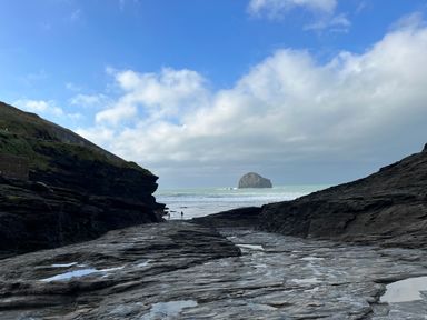 A rocky coastline with cliffs and a large rock formation in the sea at Goose Cottage - within the Helland Barton Farm collection in Delabole