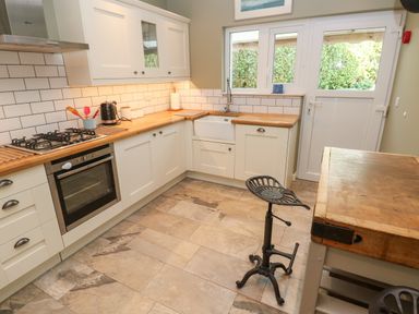 A kitchen with white cabinets wooden countertops and tiled floor at Sandtop in Tenby