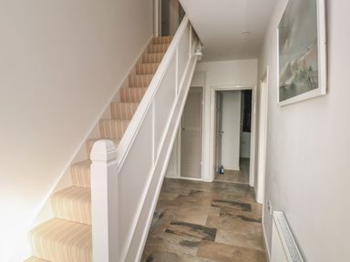 A hallway with a beige carpeted staircase radiator and a framed picture on the wall at Sandtop in Tenby