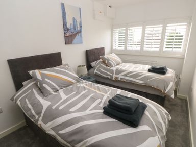 A bedroom with two single beds with patterned bedding and folded towels on each bed at Sandtop in Tenby