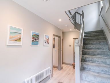 A hallway with carpeted stairs and framed pictures on the wall at 41 Chatsworth Gardens in Scarborough