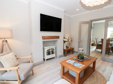 A living room with a wall-mounted television a wooden coffee table and a gray armchair at 41 Chatsworth Gardens Scarborough