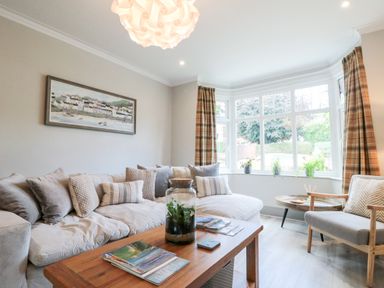 A living room with a sofa an armchair a wooden coffee table and plants on the window at 41 Chatsworth Gardens in Scarborough