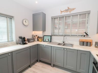 A kitchen with grey cabinets a double sink a coffee machine and a shark wall decoration at 41 Chatsworth Gardens in Scarborough