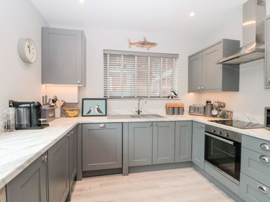 A kitchen with gray cabinets a double sink a coffee machine and an oven at 41 Chatsworth Gardens in Scarborough