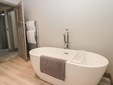 A freestanding bathtub with a faucet and a towel on it in a bathroom with an open door and towel rack at 41 Chatsworth Gardens in Scarborough