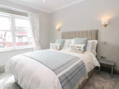 A bedroom with a bed with pillows and a blue blanket by a window at 41 Chatsworth Gardens in Scarborough