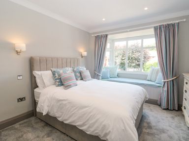 A bedroom with a bed and pillows next to a window seat with cushions and curtains at 41 Chatsworth Gardens in Scarborough
