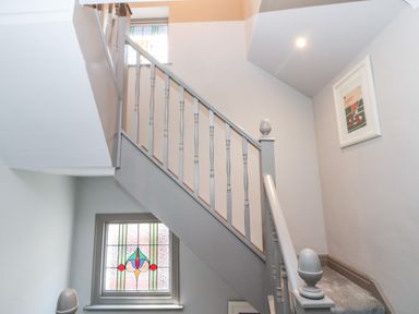 A stairway with grey painted banisters and stained glass windows at 41 Chatsworth Gardens in Scarborough